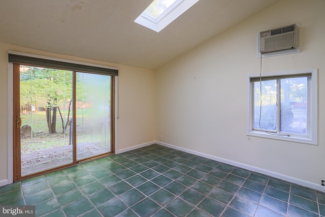 spare room featuring baseboards, vaulted ceiling with skylight, a wall mounted air conditioner, and a healthy amount of sunlight