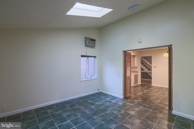 unfurnished room featuring a textured ceiling, a wall unit AC, a skylight, and baseboards