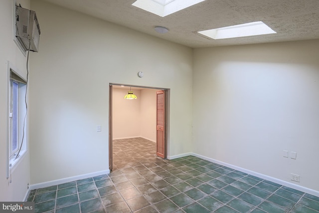 empty room featuring lofted ceiling with skylight, a textured ceiling, and baseboards