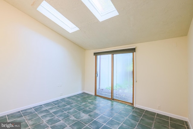 spare room with a textured ceiling, vaulted ceiling with skylight, and baseboards