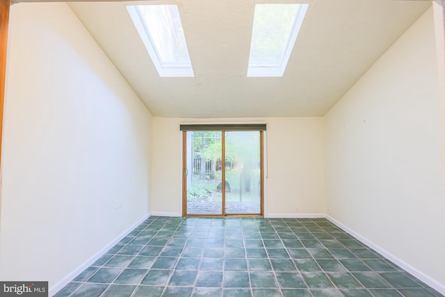 spare room featuring lofted ceiling with skylight and baseboards