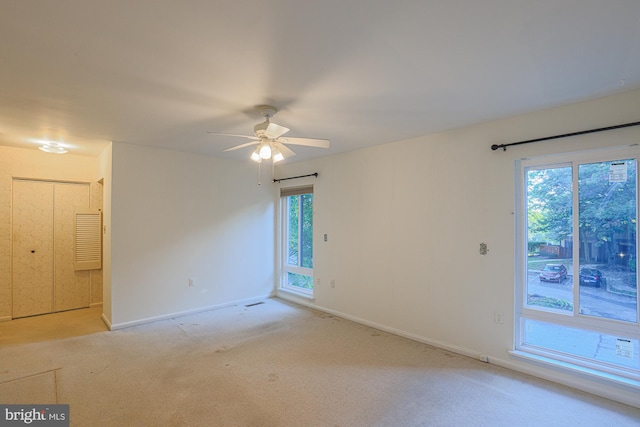 spare room with a ceiling fan, light carpet, and baseboards