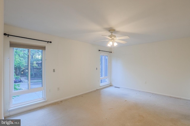 unfurnished room featuring ceiling fan, visible vents, baseboards, and light colored carpet