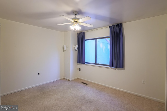 carpeted spare room with a ceiling fan, visible vents, and baseboards