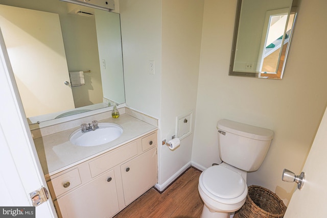 bathroom with baseboards, vanity, toilet, and wood finished floors