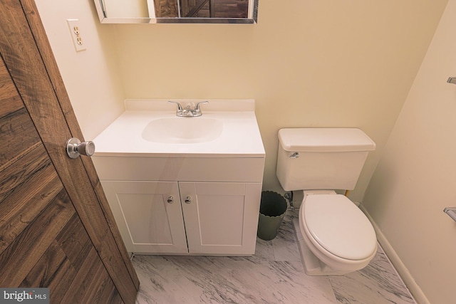 half bathroom with toilet, marble finish floor, and vanity