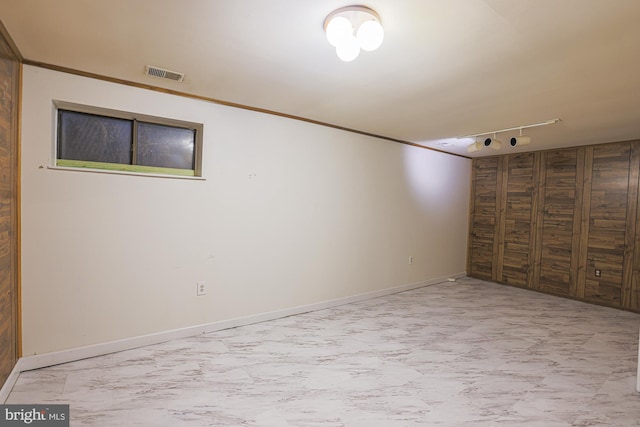 finished basement featuring marble finish floor, baseboards, visible vents, and crown molding