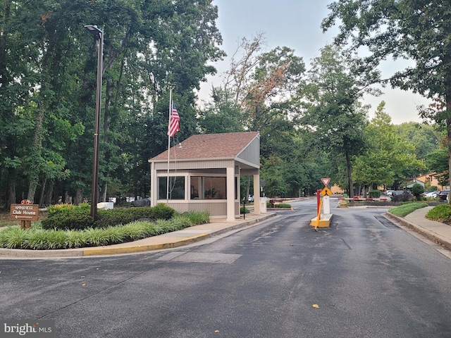 view of road featuring street lights, traffic signs, sidewalks, a gated entry, and curbs