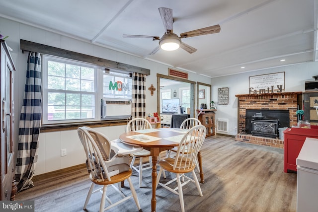 dining area featuring hardwood / wood-style flooring, a brick fireplace, cooling unit, and ceiling fan