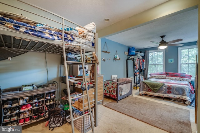 bedroom with a textured ceiling, light colored carpet, and ceiling fan