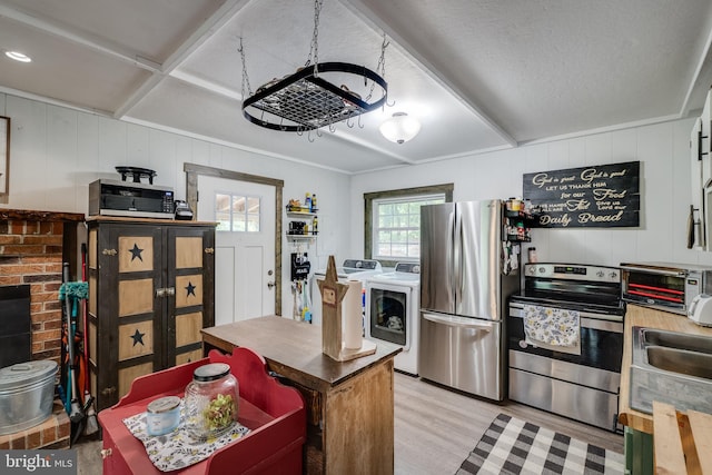 kitchen featuring light hardwood / wood-style floors, appliances with stainless steel finishes, sink, and washing machine and clothes dryer