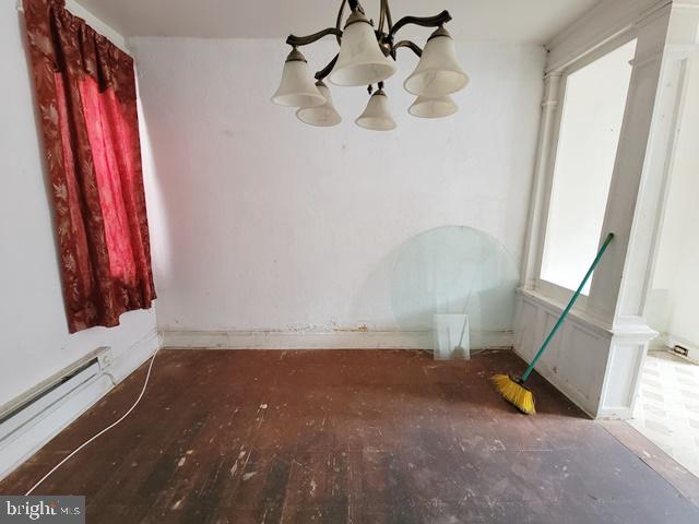 empty room featuring a baseboard radiator, an inviting chandelier, and wood-type flooring