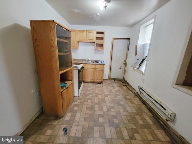 kitchen with light tile patterned floors, a baseboard radiator, light brown cabinetry, white stove, and sink