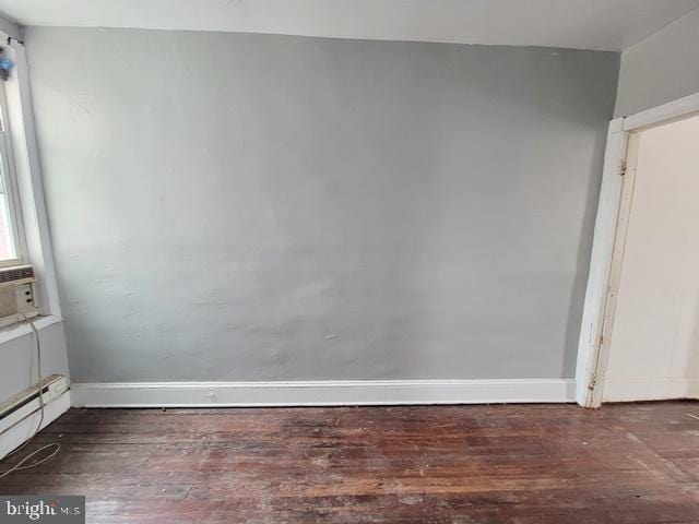 empty room featuring baseboard heating and wood-type flooring