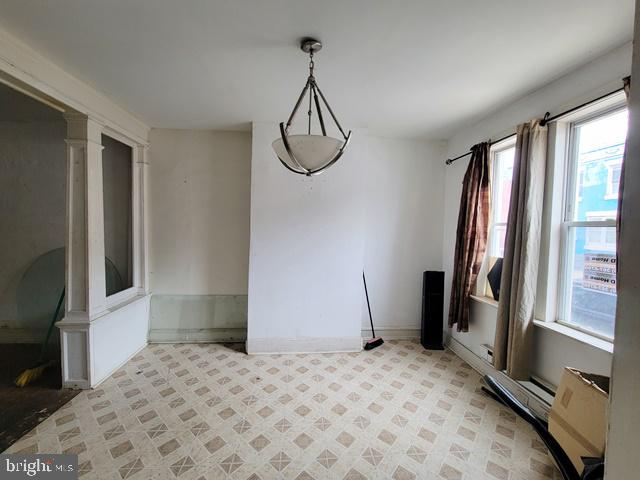 tiled spare room featuring decorative columns and a wealth of natural light