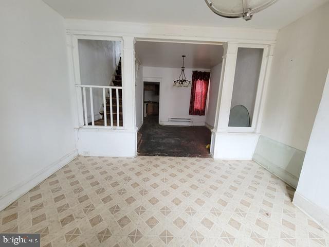 spare room with tile patterned floors, decorative columns, and baseboard heating