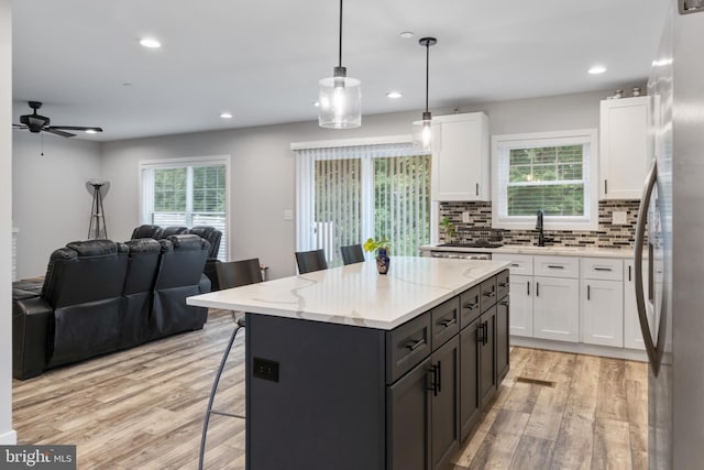 kitchen with a wealth of natural light, tasteful backsplash, white cabinets, and light hardwood / wood-style floors