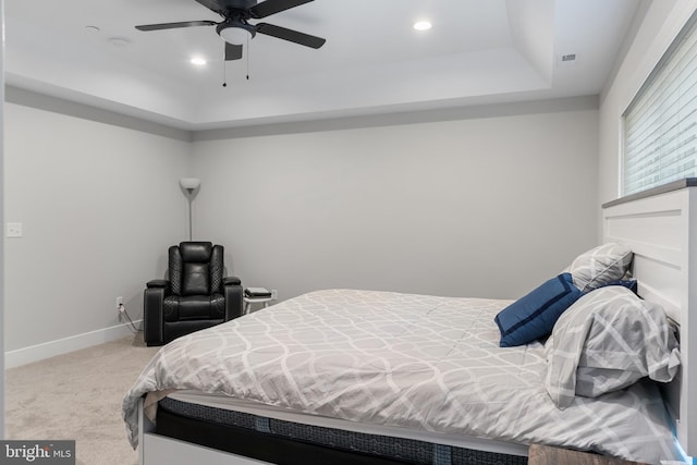 carpeted bedroom featuring ceiling fan and a raised ceiling