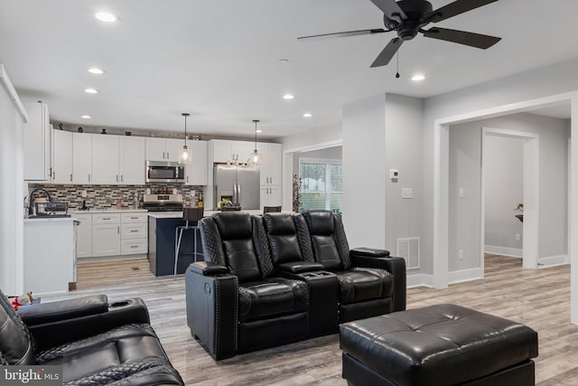 living room with sink, light wood-type flooring, and ceiling fan