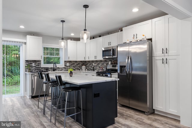 kitchen with a healthy amount of sunlight, light stone counters, appliances with stainless steel finishes, and light wood-type flooring