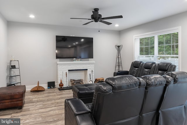 living room with a fireplace, light wood-type flooring, and ceiling fan