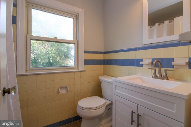 bathroom featuring tile patterned floors, vanity, tile walls, and toilet