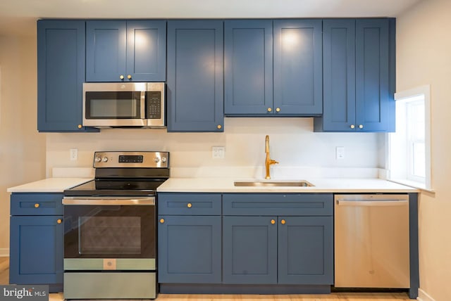 kitchen with light hardwood / wood-style flooring, stainless steel appliances, sink, and blue cabinetry