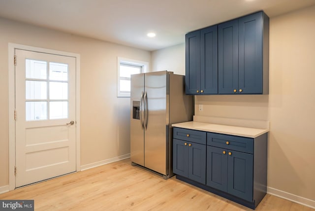 kitchen featuring blue cabinetry, stainless steel fridge, a healthy amount of sunlight, and light hardwood / wood-style floors