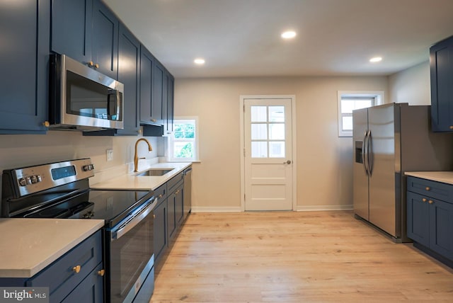 kitchen with appliances with stainless steel finishes, light hardwood / wood-style flooring, sink, and a healthy amount of sunlight