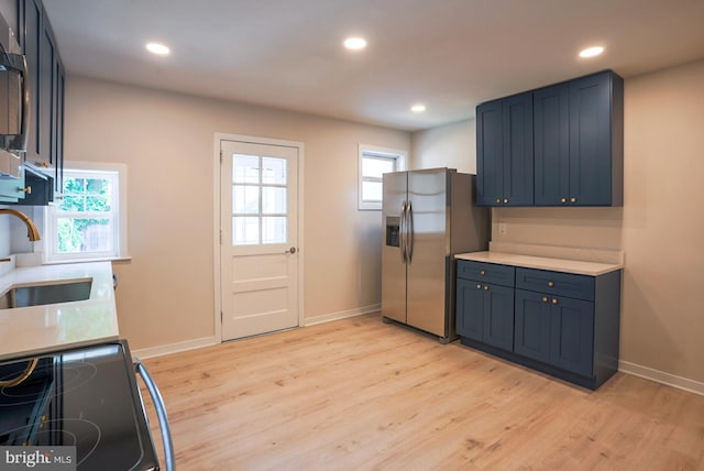 kitchen featuring light wood-type flooring, stainless steel refrigerator with ice dispenser, a wealth of natural light, and sink