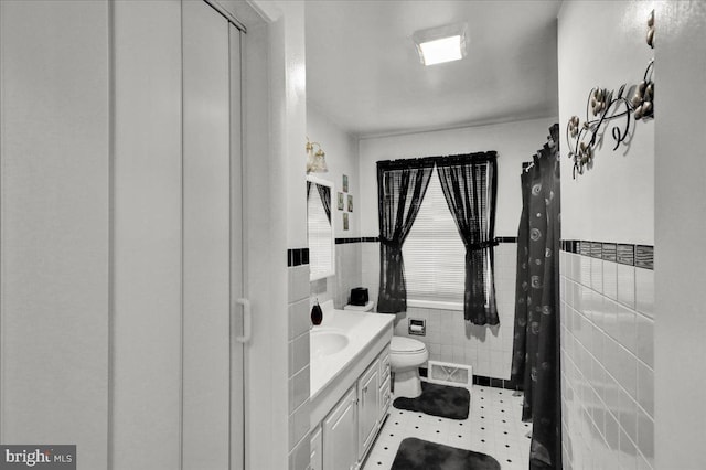 bathroom featuring tile walls, vanity, and toilet