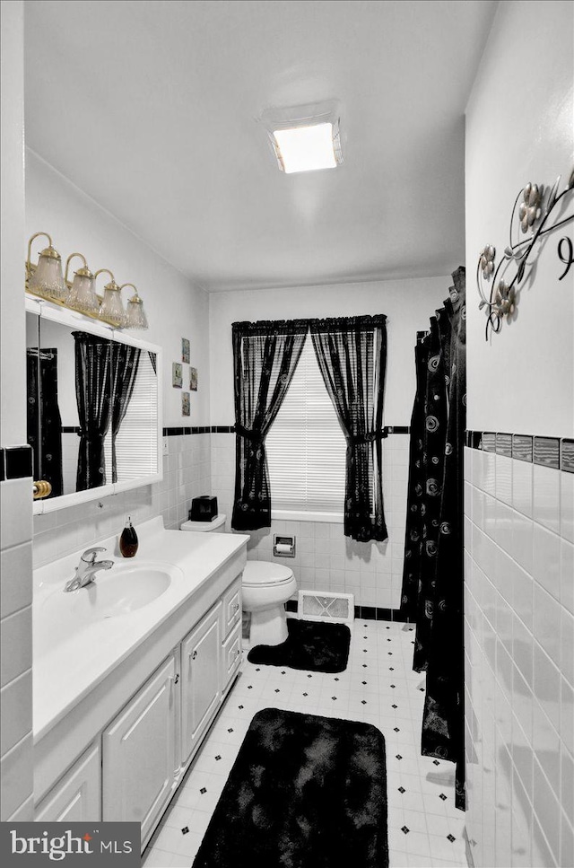 bathroom featuring vanity, tile patterned flooring, toilet, and tile walls