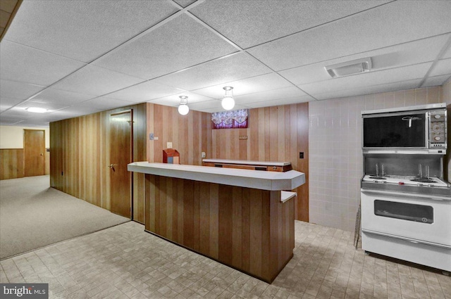 bar featuring white electric range, a drop ceiling, and wood walls