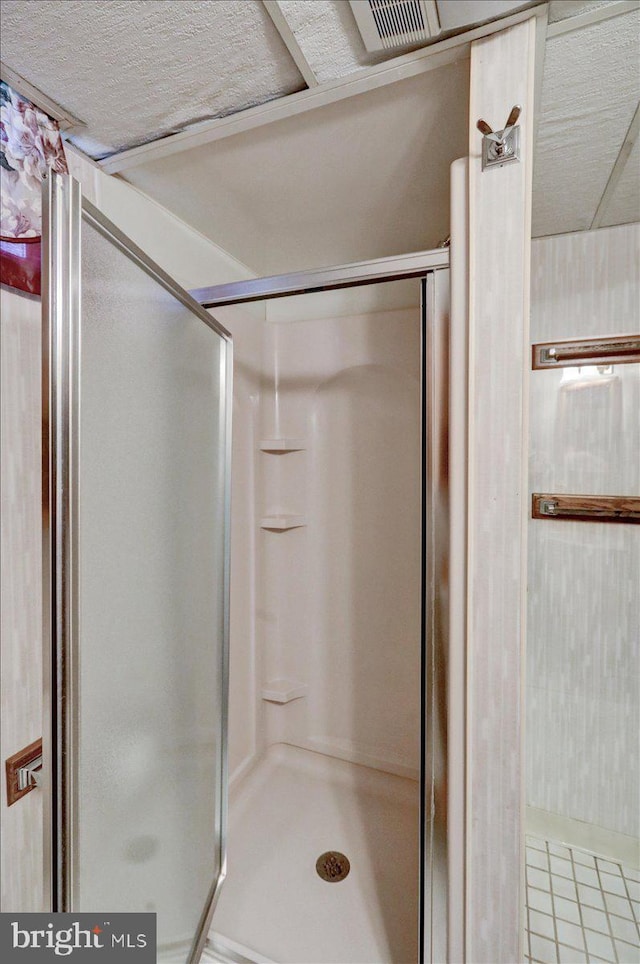 bathroom with walk in shower, tile patterned flooring, and a textured ceiling