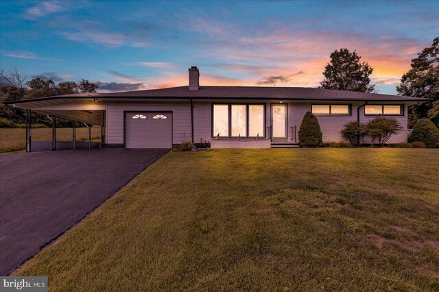 ranch-style home with a carport, a garage, and a yard