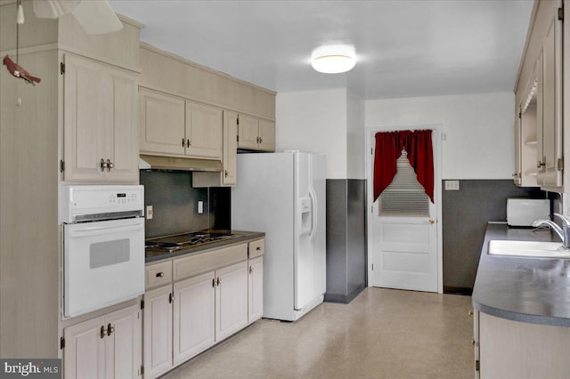 kitchen with cream cabinets, sink, tasteful backsplash, and white appliances