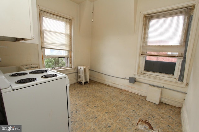 kitchen with radiator heating unit, light tile patterned floors, white range with electric stovetop, and white cabinetry