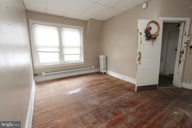 unfurnished room featuring radiator, a baseboard heating unit, hardwood / wood-style flooring, and a drop ceiling