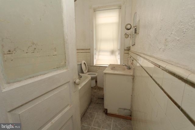 bathroom with tile patterned floors, vanity, tile walls, and toilet