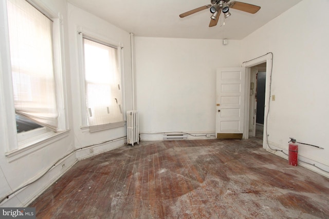 empty room with ceiling fan, radiator, and hardwood / wood-style floors