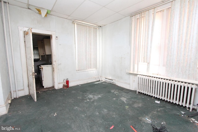 spare room featuring radiator and a paneled ceiling