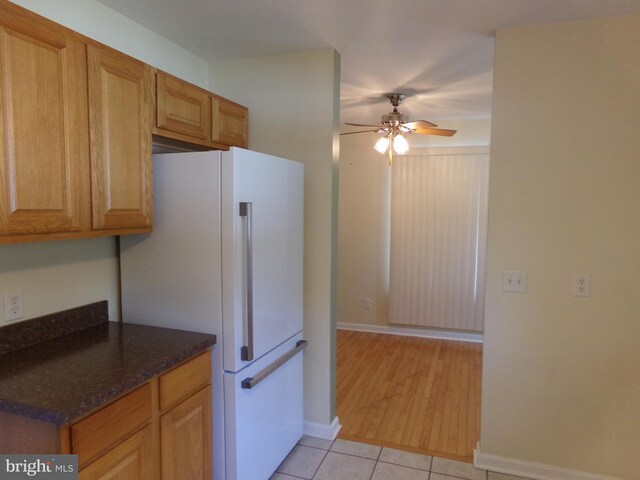 kitchen with dark stone counters, light wood-type flooring, ceiling fan, and white refrigerator