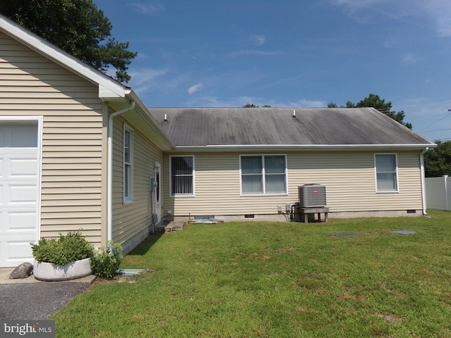 back of house featuring central AC unit, a garage, and a yard