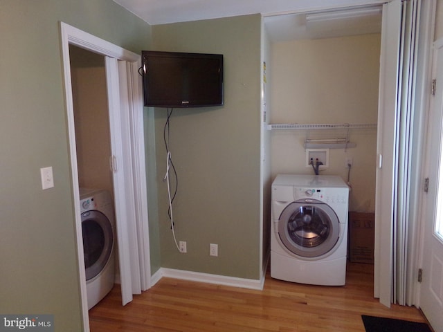 clothes washing area featuring light hardwood / wood-style flooring and washer / clothes dryer