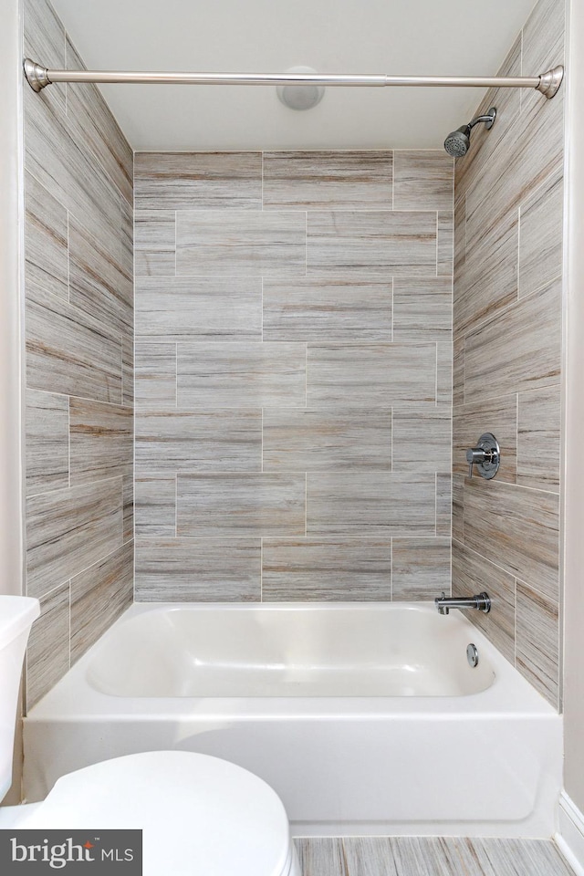 bathroom featuring toilet and tiled shower / bath combo