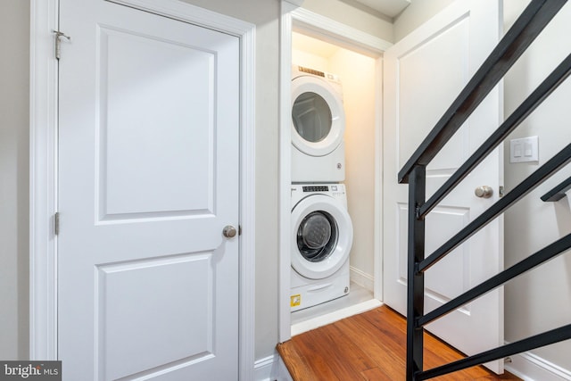 clothes washing area featuring stacked washer and dryer and hardwood / wood-style flooring