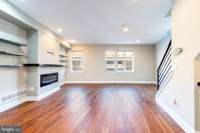 unfurnished living room featuring hardwood / wood-style flooring and built in features