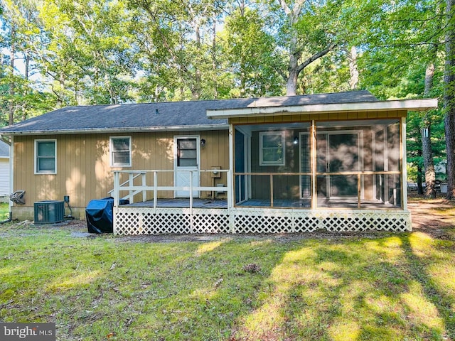 rear view of property with a sunroom, central AC unit, and a lawn