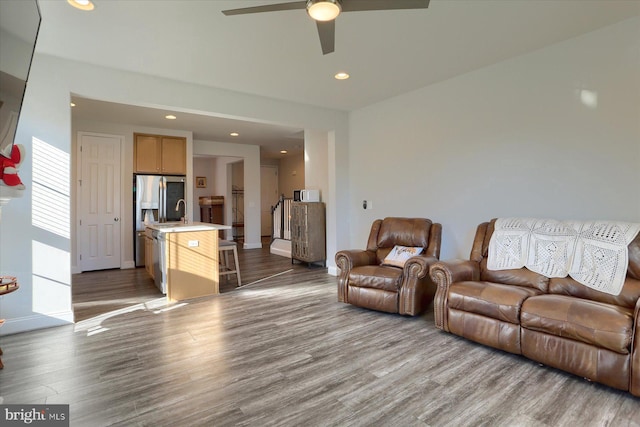 living room featuring ceiling fan, sink, and light hardwood / wood-style floors