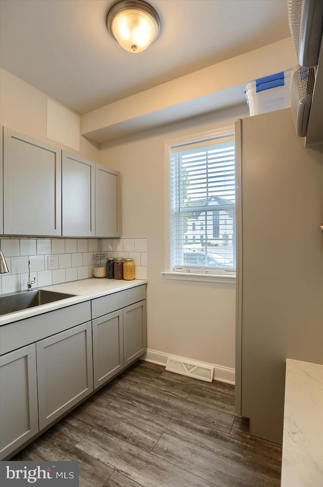 kitchen with gray cabinetry, sink, backsplash, and dark hardwood / wood-style floors